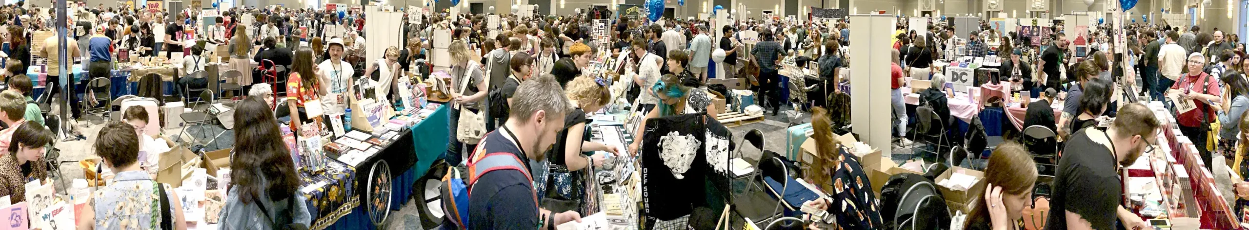 A wide panoramic shot of the exhibition floor at SPX showing lots of guests visiting exhibition tables full of great independent comics.